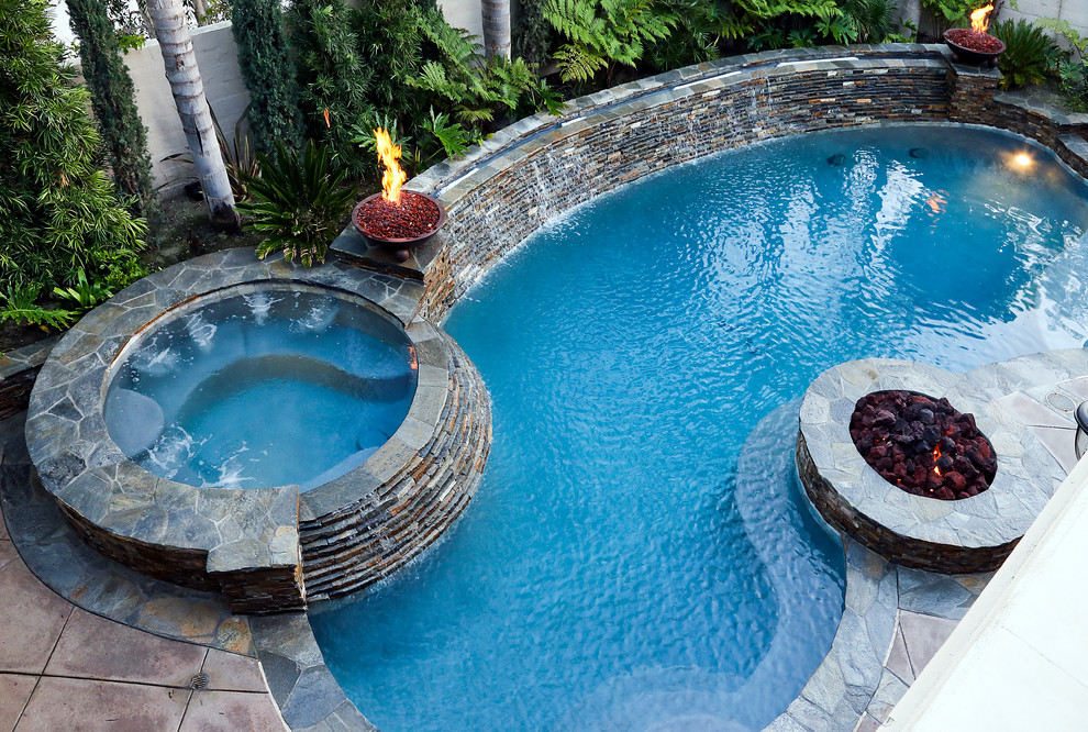 Foto de piscinas y jacuzzis alargados clásicos de tamaño medio tipo riñón en patio trasero con losas de hormigón