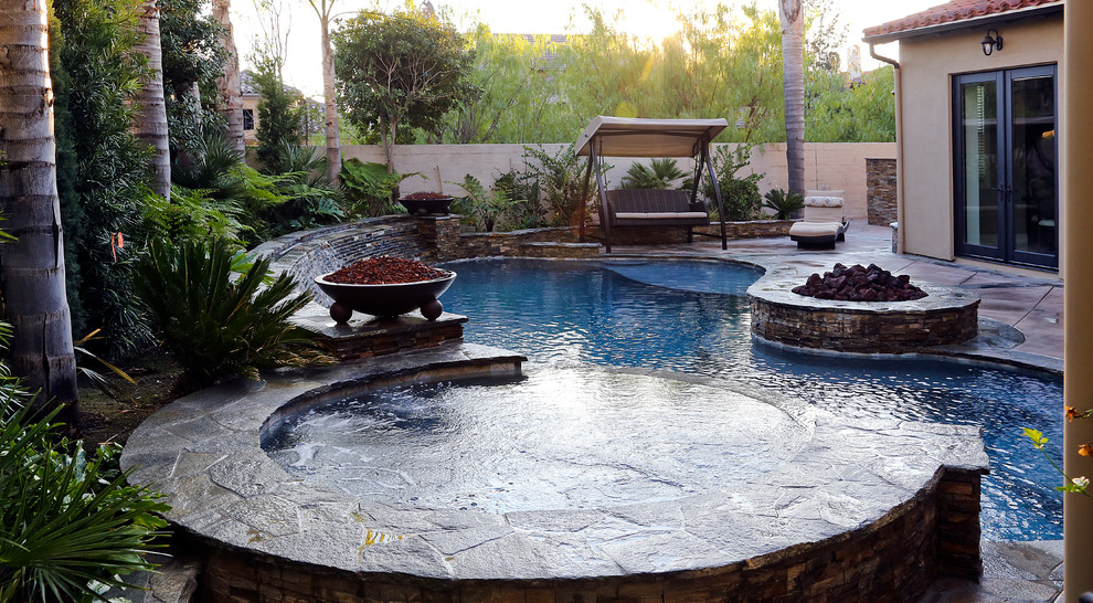 Example of a mid-sized classic backyard concrete and kidney-shaped lap hot tub design in Orange County