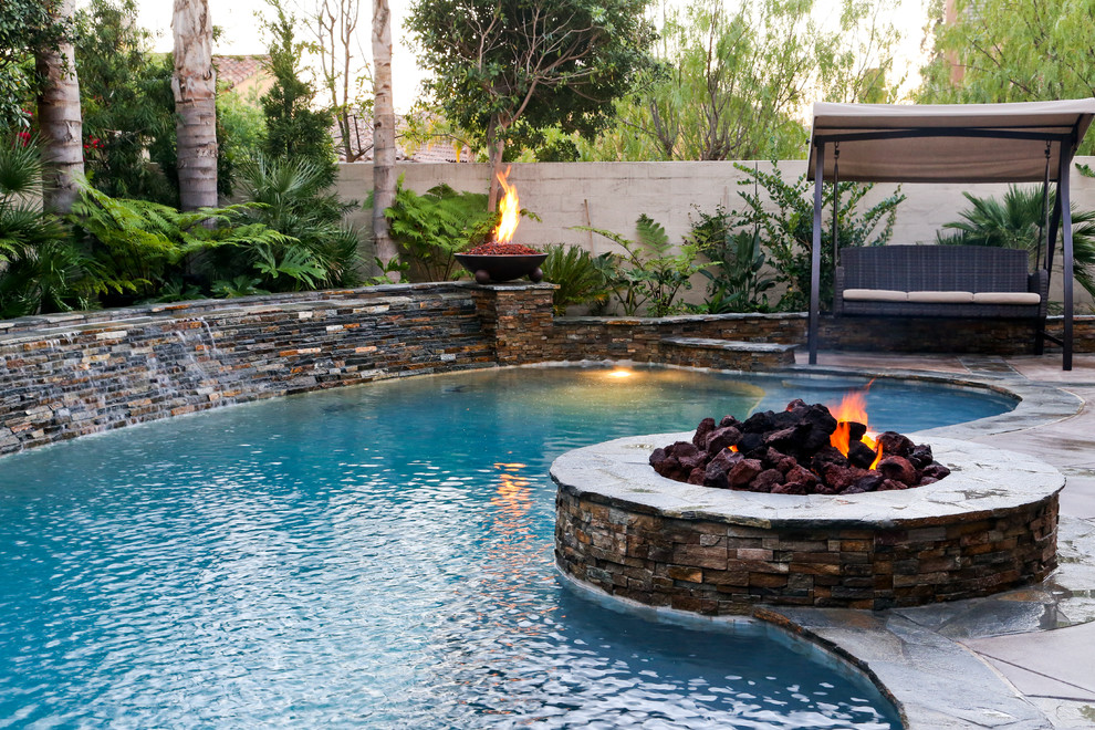 Foto de piscina con fuente alargada clásica de tamaño medio tipo riñón en patio trasero con losas de hormigón