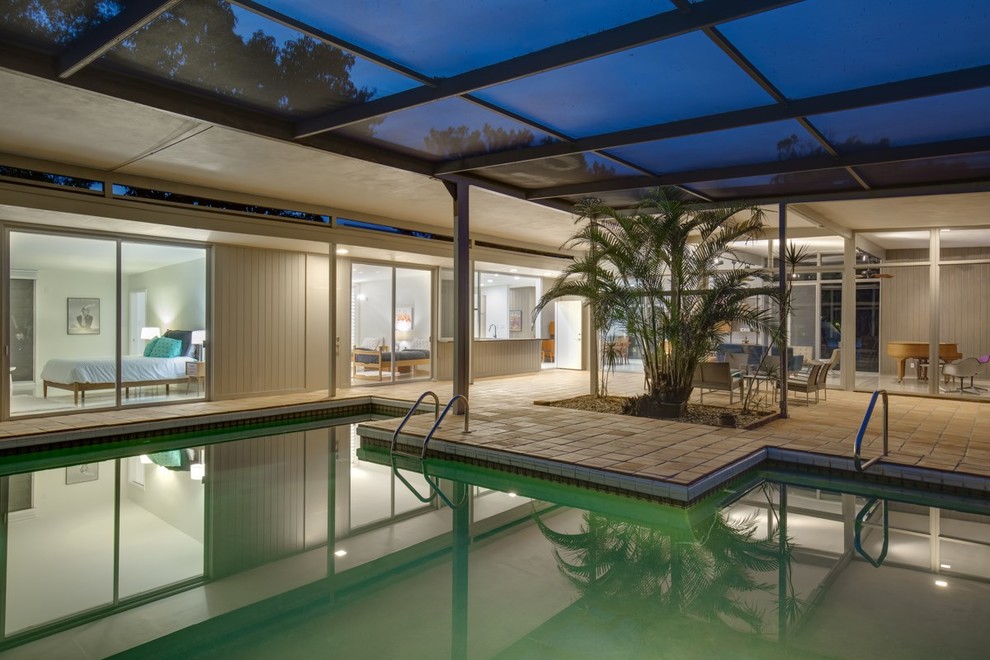 Ejemplo de casa de la piscina y piscina alargada actual de tamaño medio a medida en patio trasero con suelo de baldosas