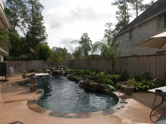 Imagen de piscinas y jacuzzis clásicos grandes a medida en patio trasero con losas de hormigón