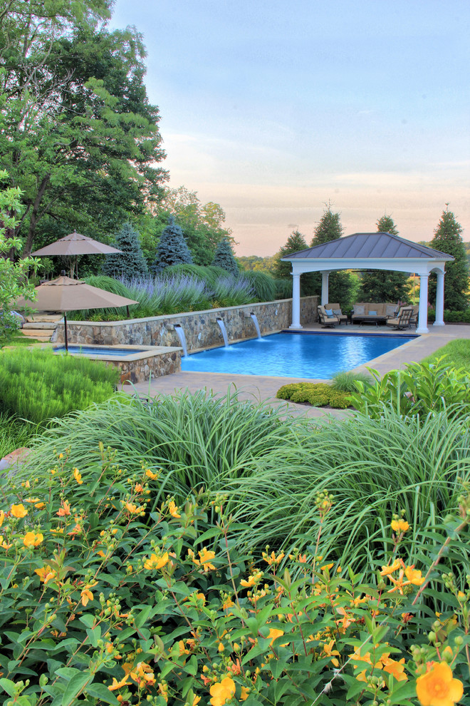 Immagine di una piscina monocorsia classica rettangolare di medie dimensioni e dietro casa con fontane