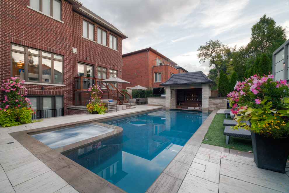 Idee per una grande piscina moderna rettangolare dietro casa con fontane e pavimentazioni in pietra naturale