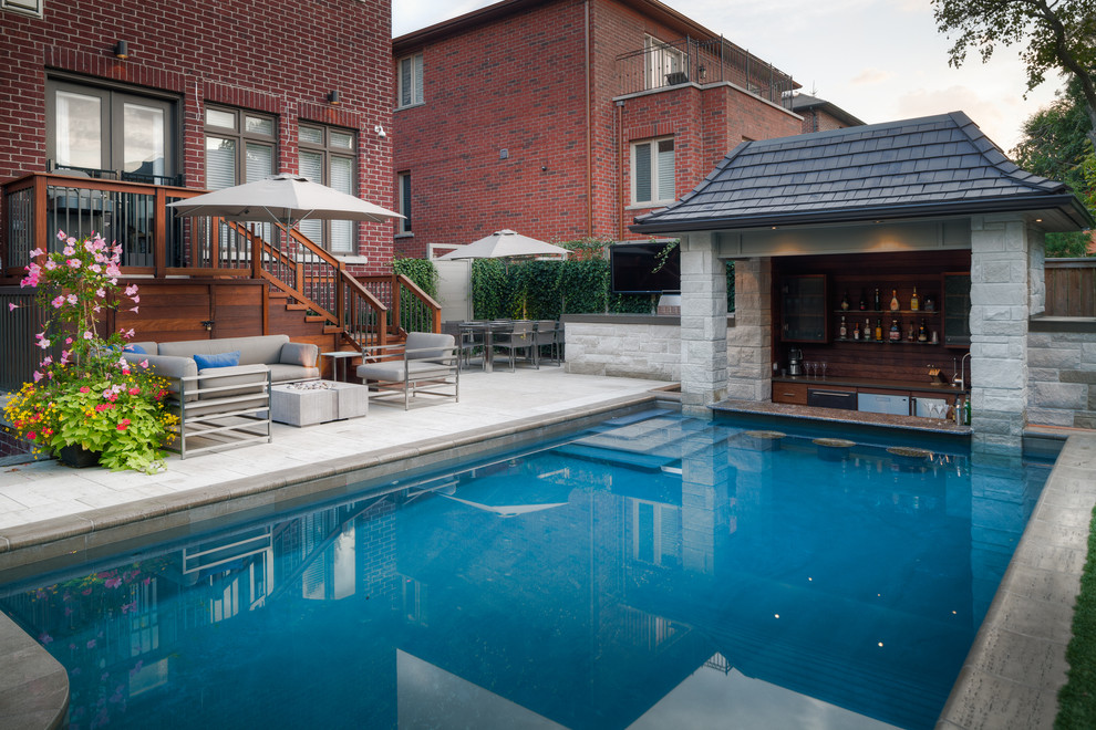 На фото: большой прямоугольный бассейн на заднем дворе в стиле модернизм с фонтаном и покрытием из каменной брусчатки