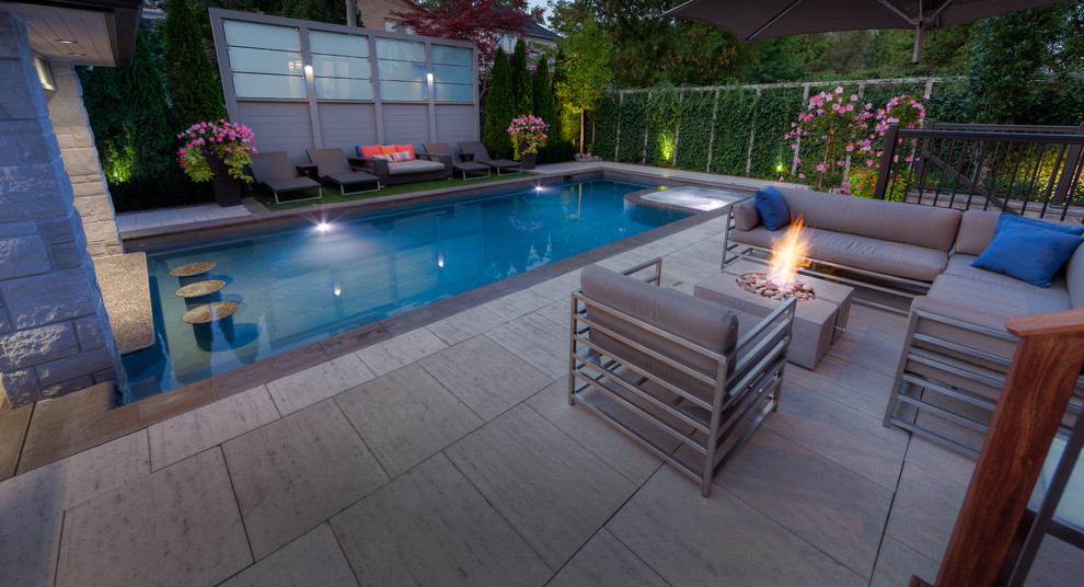 Ejemplo de piscina con fuente minimalista grande rectangular en patio trasero con adoquines de piedra natural
