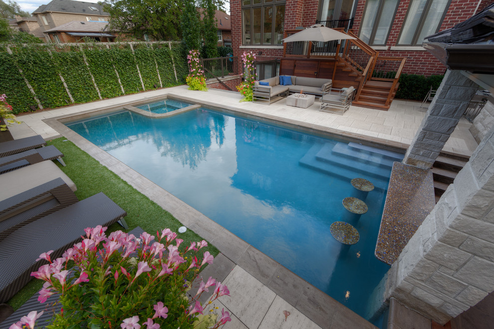 Imagen de piscina con fuente minimalista grande rectangular en patio trasero con adoquines de piedra natural