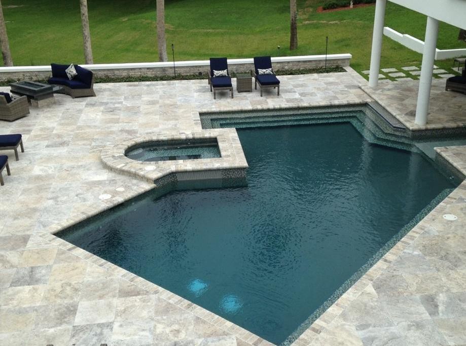 Foto di una grande piscina monocorsia tropicale a "C" dietro casa con pavimentazioni in pietra naturale