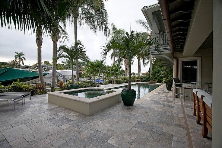 Ejemplo de piscina alargada tropical de tamaño medio rectangular en patio trasero con adoquines de piedra natural