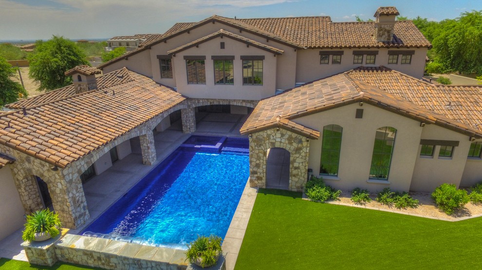 Esempio di una grande piscina monocorsia stile americano rettangolare dietro casa con una vasca idromassaggio e pavimentazioni in pietra naturale