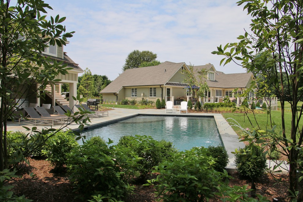 Immagine di una grande piscina chic rettangolare dietro casa con pavimentazioni in pietra naturale