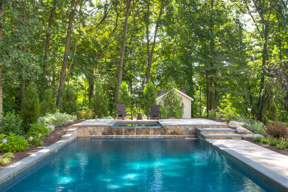 Idee per una piscina monocorsia tradizionale rettangolare dietro casa con una vasca idromassaggio e pavimentazioni in pietra naturale