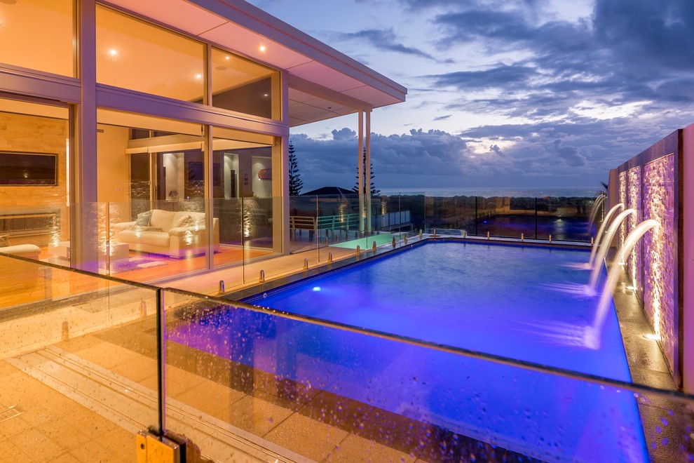 Ejemplo de piscina con fuente alargada contemporánea de tamaño medio rectangular en patio lateral con suelo de baldosas