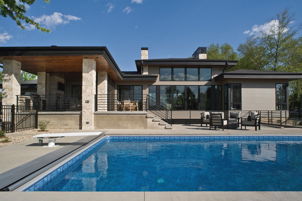 Diseño de piscina moderna grande rectangular en patio trasero con losas de hormigón