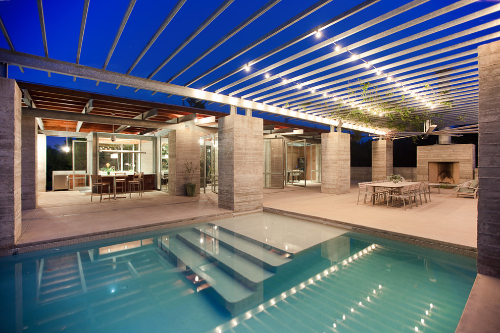 Modelo de casa de la piscina y piscina alargada contemporánea de tamaño medio rectangular en patio trasero con losas de hormigón