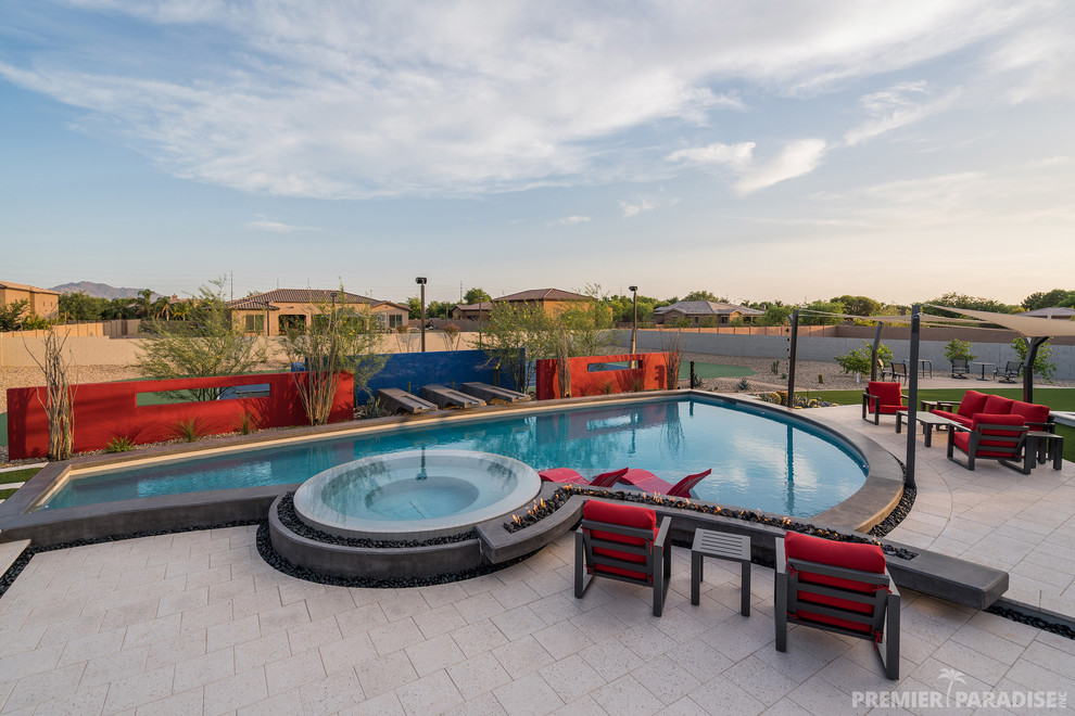 Immagine di una grande piscina a sfioro infinito design personalizzata dietro casa con pavimentazioni in pietra naturale