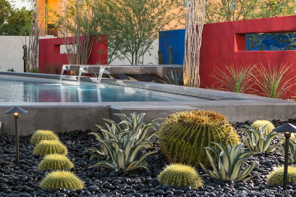 Diseño de piscina infinita contemporánea grande a medida en patio trasero con adoquines de piedra natural