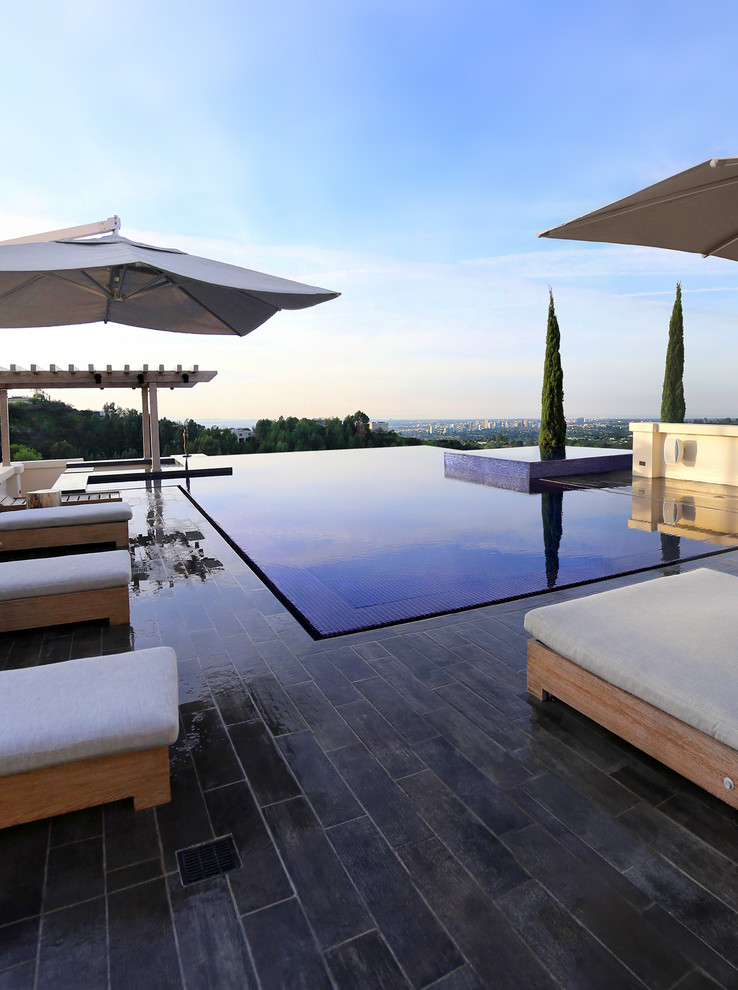 Photo of a large modern back rectangular infinity swimming pool in Los Angeles with a water feature and tiled flooring.