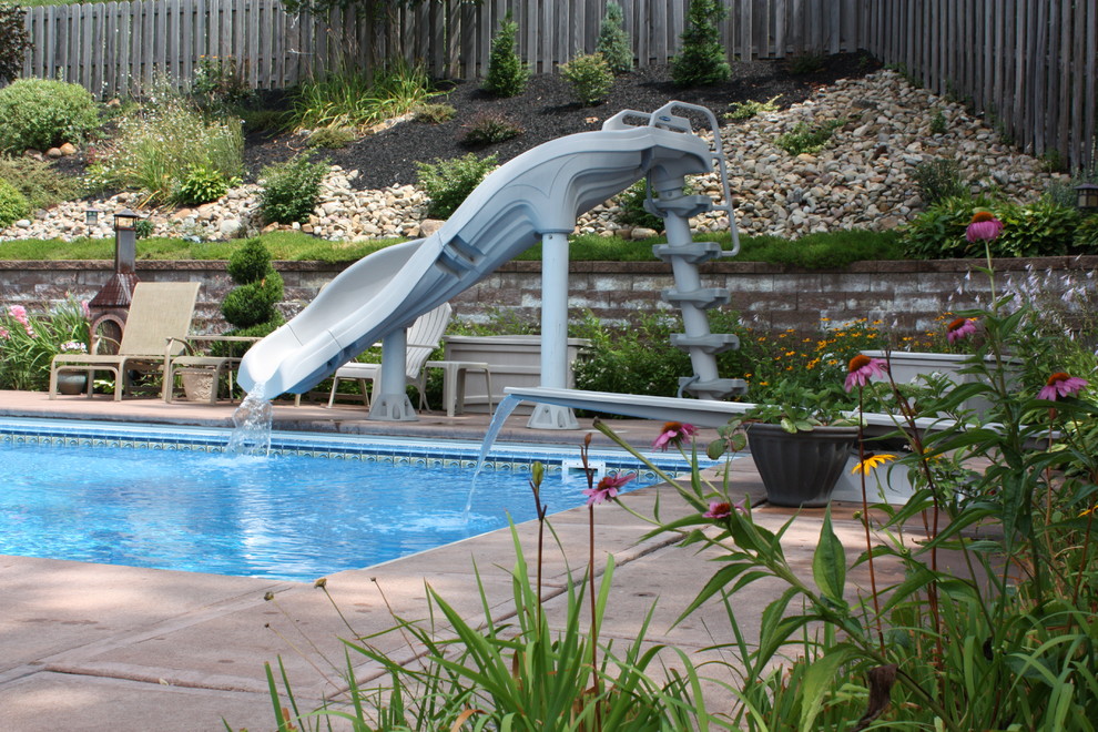 На фото: спортивный, прямоугольный бассейн среднего размера на заднем дворе в классическом стиле с водной горкой и покрытием из каменной брусчатки