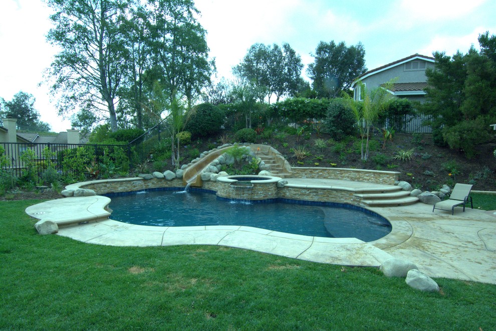 Inspiration for a mid-sized tropical backyard stamped concrete and custom-shaped water slide remodel in Los Angeles