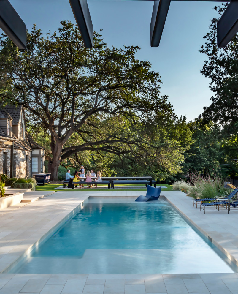 Photo of a medium sized modern back rectangular swimming pool in Austin with with pool landscaping and natural stone paving.