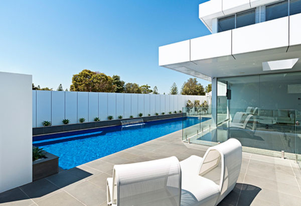Imagen de piscina con fuente alargada minimalista grande a medida en patio lateral con adoquines de piedra natural