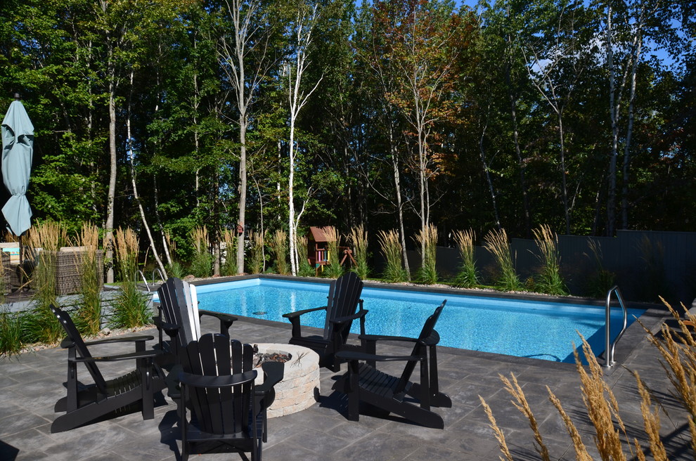 Ejemplo de piscina actual de tamaño medio rectangular en patio trasero con suelo de hormigón estampado