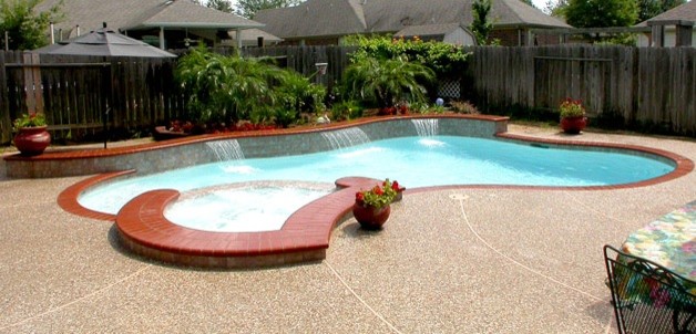 Esempio di una grande piscina chic personalizzata dietro casa con una vasca idromassaggio e lastre di cemento