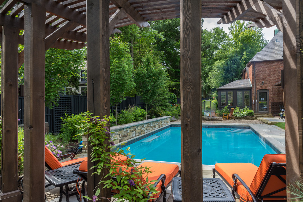 Foto de piscina con fuente alargada clásica de tamaño medio rectangular en patio trasero con adoquines de piedra natural