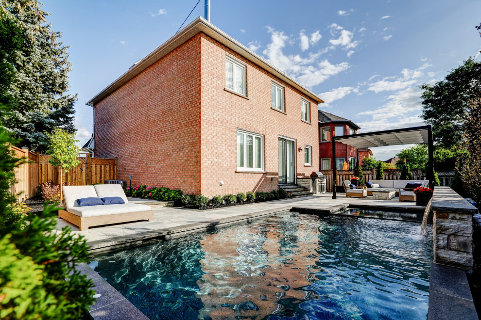 Ejemplo de piscinas y jacuzzis clásicos renovados pequeños rectangulares en patio trasero con adoquines de piedra natural