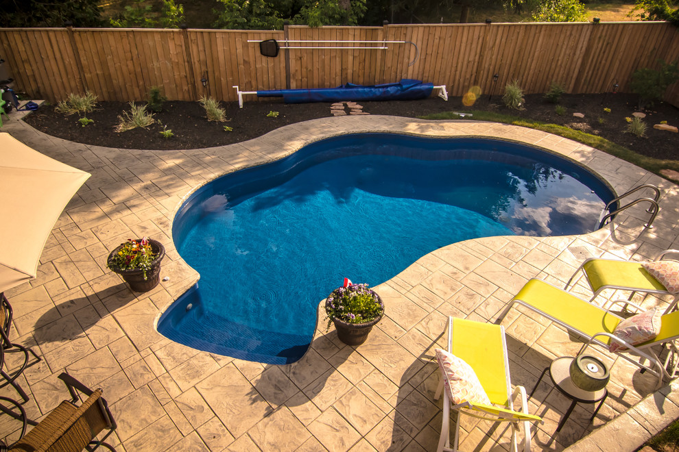 Foto di una grande piscina chic personalizzata dietro casa con cemento stampato
