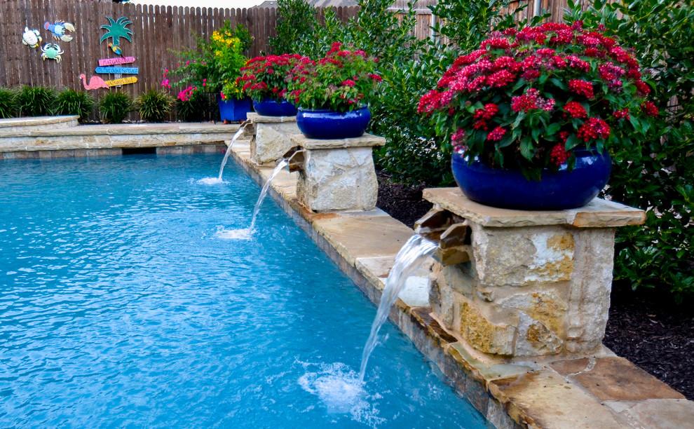 Ejemplo de piscina con fuente alargada tradicional pequeña a medida en patio trasero con adoquines de piedra natural