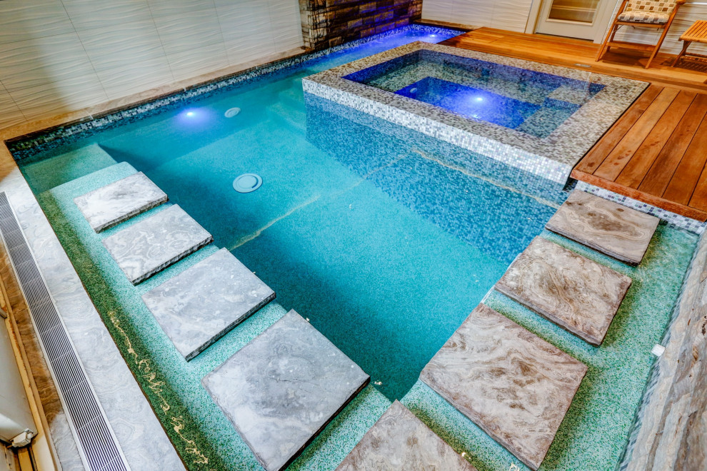 Cette photo montre une petite piscine intérieure éclectique rectangle avec un bain bouillonnant et une terrasse en bois.