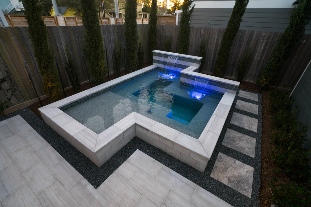 Cette image montre une petite piscine design rectangle avec un bain bouillonnant, une cour et des pavés en pierre naturelle.