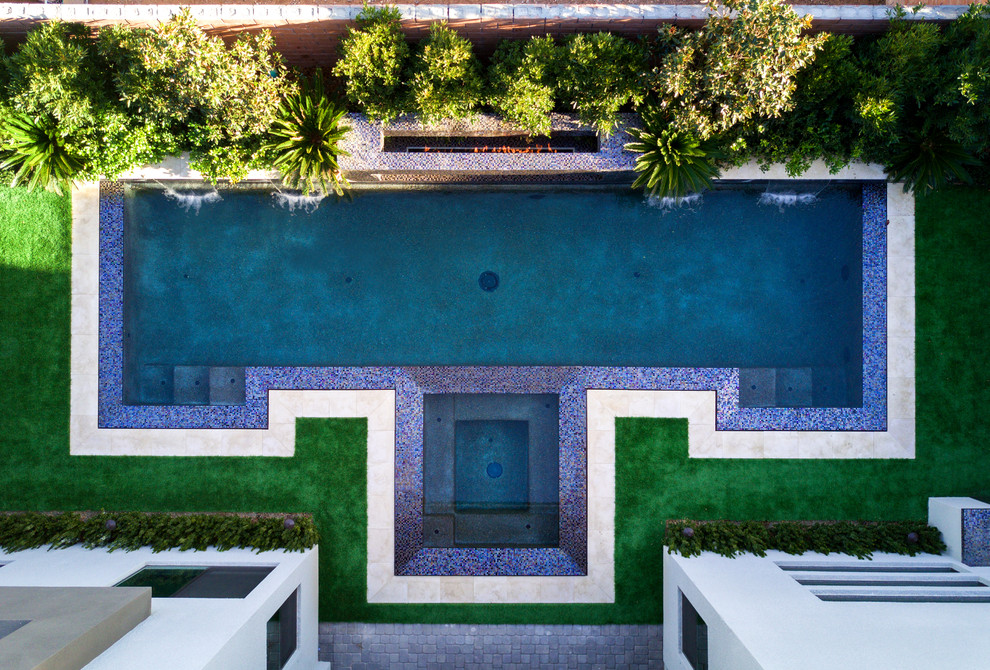 Esempio di una piccola piscina a sfioro infinito moderna personalizzata dietro casa con una vasca idromassaggio