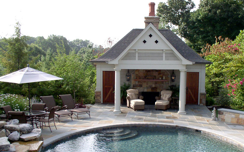 Modelo de piscina natural de estilo americano de tamaño medio redondeada en patio trasero con adoquines de piedra natural