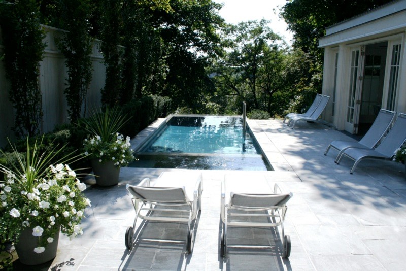 Cette image montre une petite piscine à débordement et arrière traditionnelle rectangle avec des pavés en pierre naturelle.