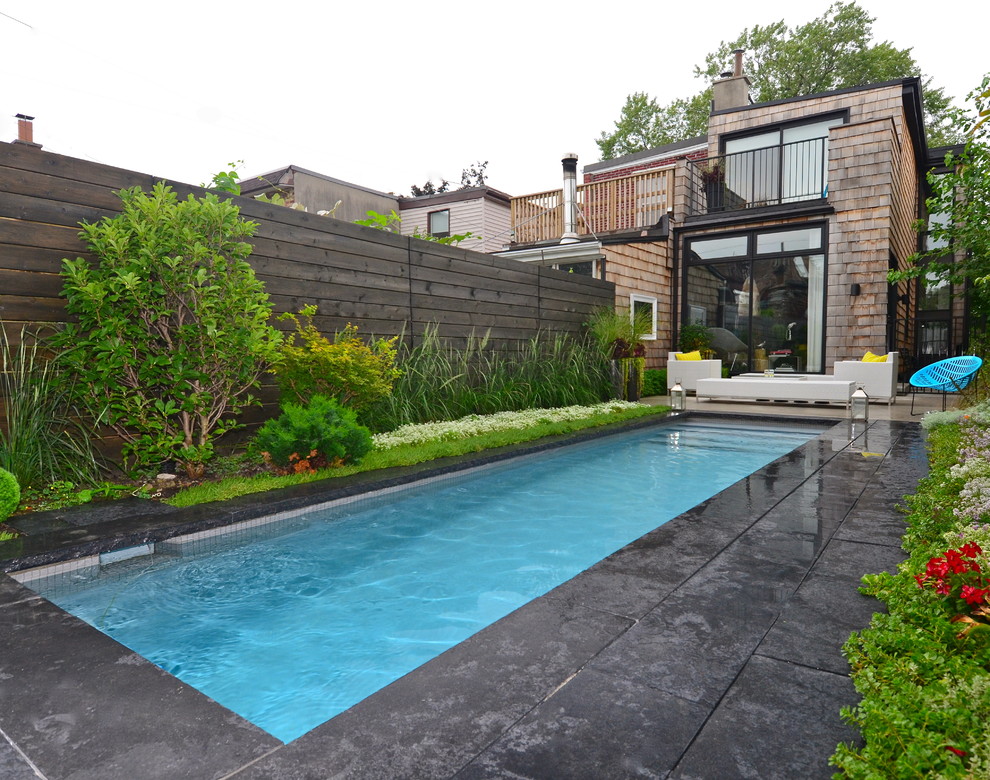This is an example of a small traditional back rectangular swimming pool in Other with natural stone paving.