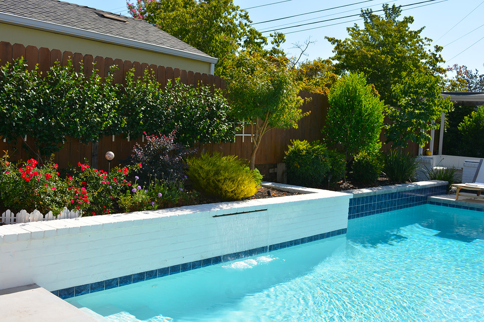 Esempio di una piccola piscina minimalista rettangolare dietro casa con fontane e pavimentazioni in cemento