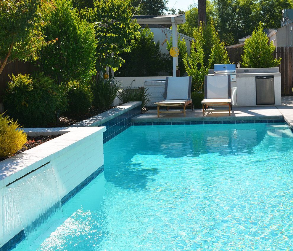 Esempio di una piccola piscina moderna rettangolare dietro casa con fontane e pavimentazioni in cemento