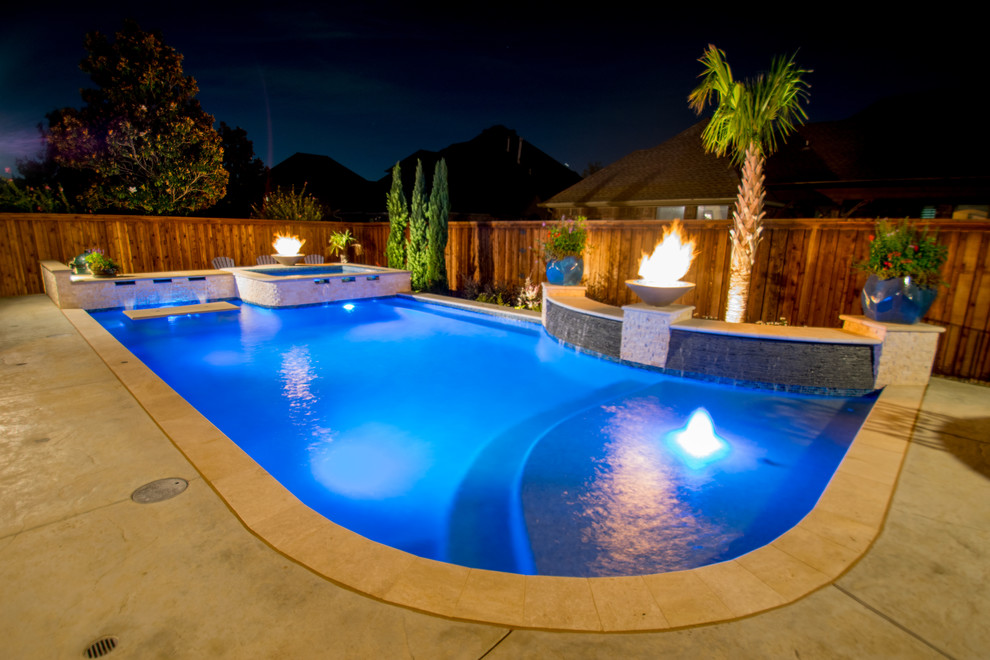 Modelo de piscina con fuente alargada tradicional renovada de tamaño medio a medida en patio trasero con suelo de hormigón estampado