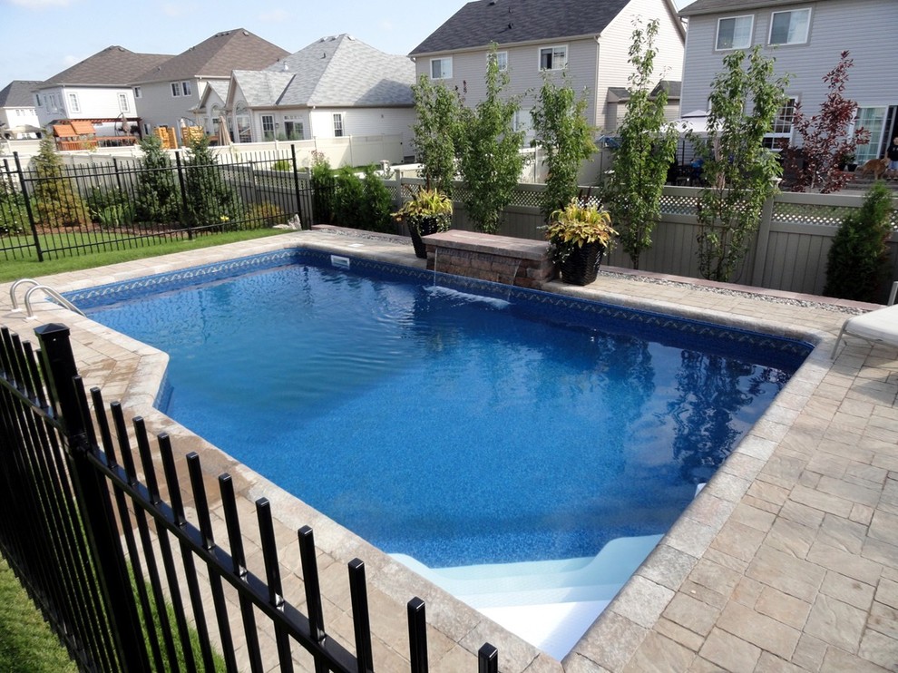 Design ideas for a small traditional back custom shaped natural swimming pool in Ottawa with a water feature and concrete paving.