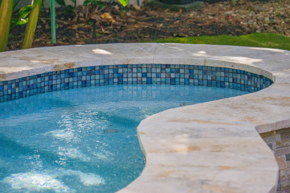 Esempio di una piscina tropicale personalizzata di medie dimensioni e dietro casa