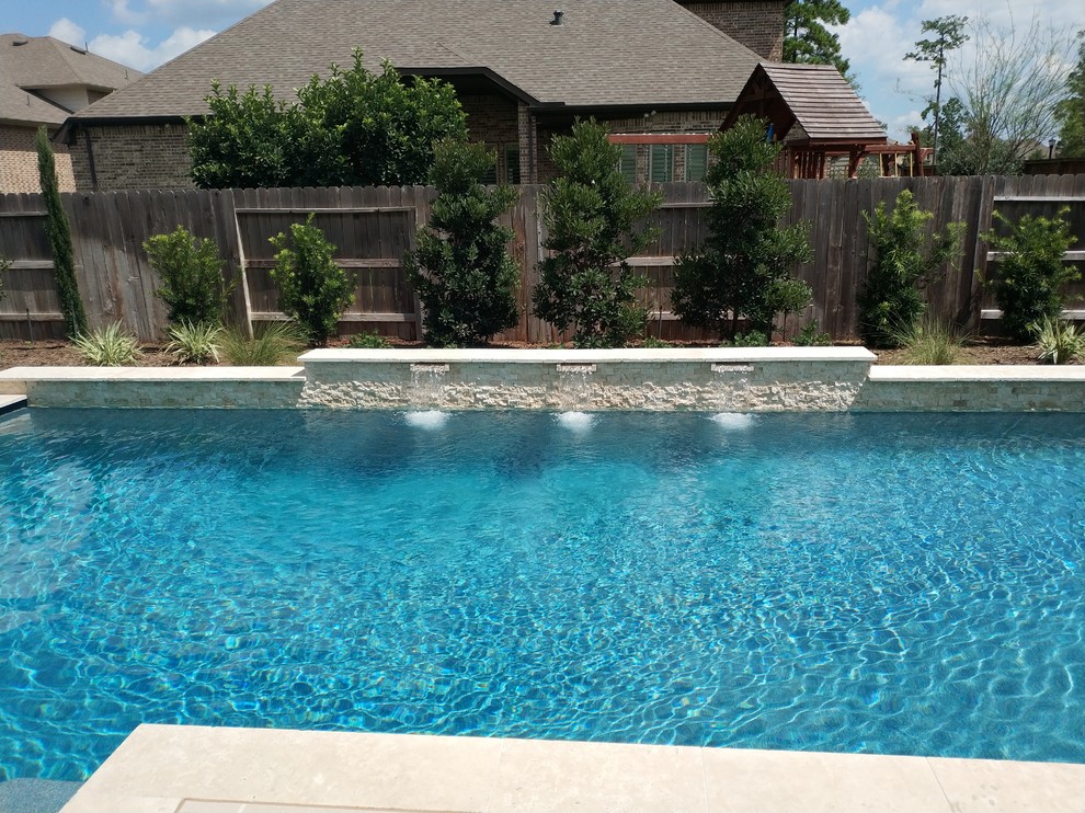 Modelo de piscinas y jacuzzis alargados clásicos renovados de tamaño medio rectangulares en patio trasero con adoquines de hormigón