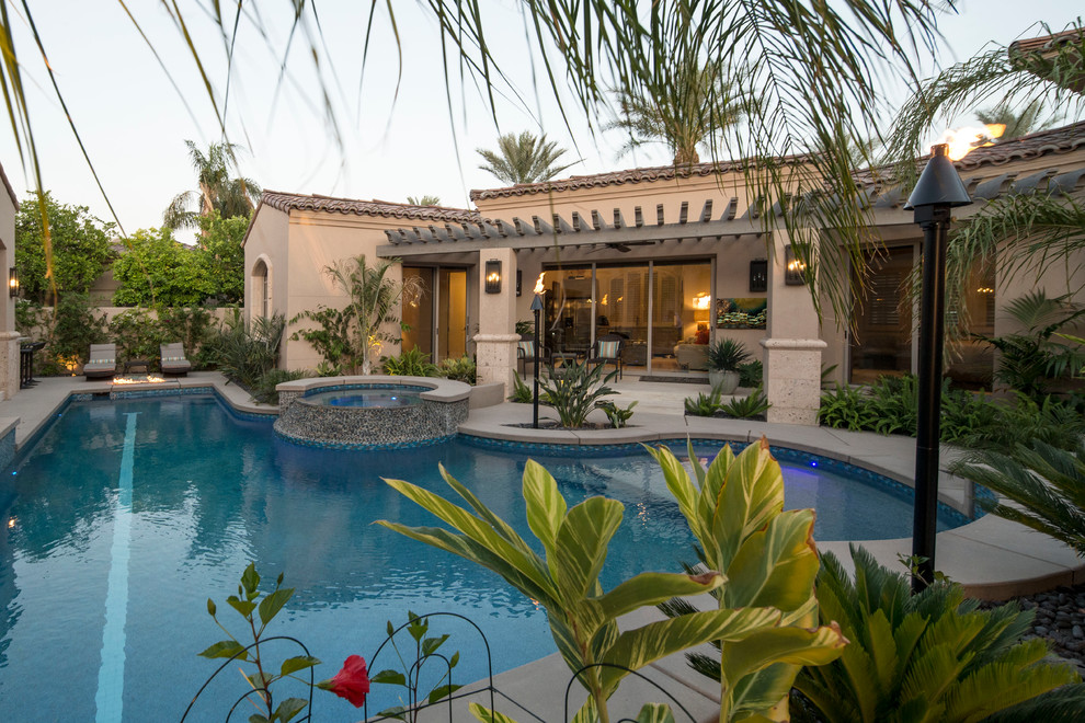 Ejemplo de piscinas y jacuzzis naturales tropicales grandes en forma de L en patio trasero con adoquines de hormigón