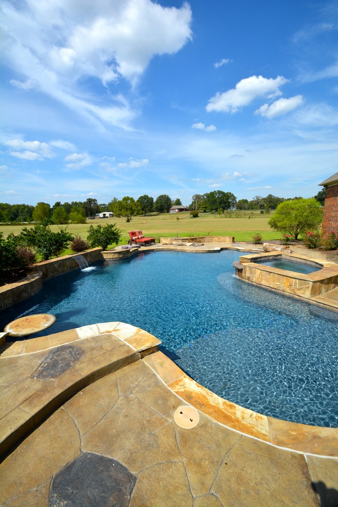 Ejemplo de piscinas y jacuzzis alargados actuales grandes a medida en patio trasero con adoquines de piedra natural