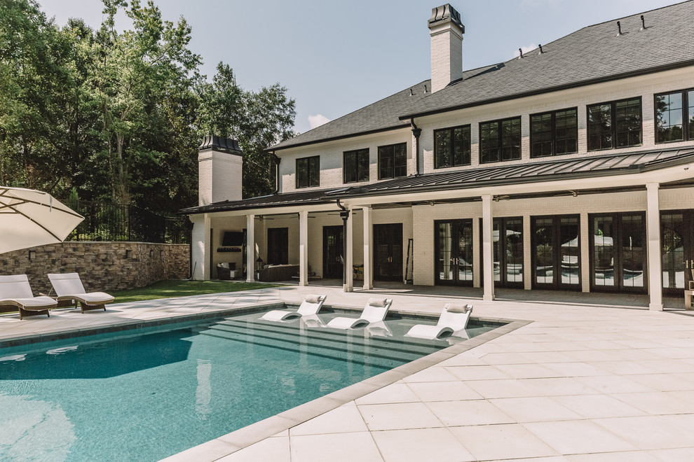 Diseño de piscina alargada tradicional renovada rectangular en patio trasero con adoquines de hormigón