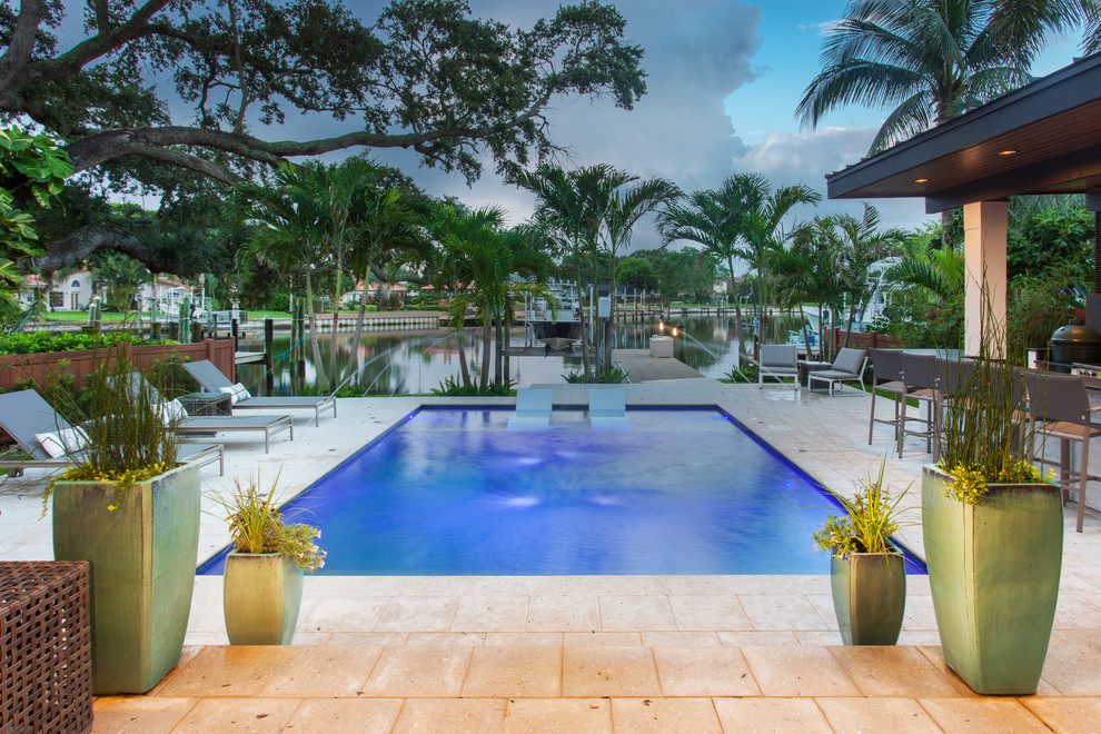 Immagine di una grande piscina monocorsia minimalista rettangolare dietro casa con pavimentazioni in pietra naturale