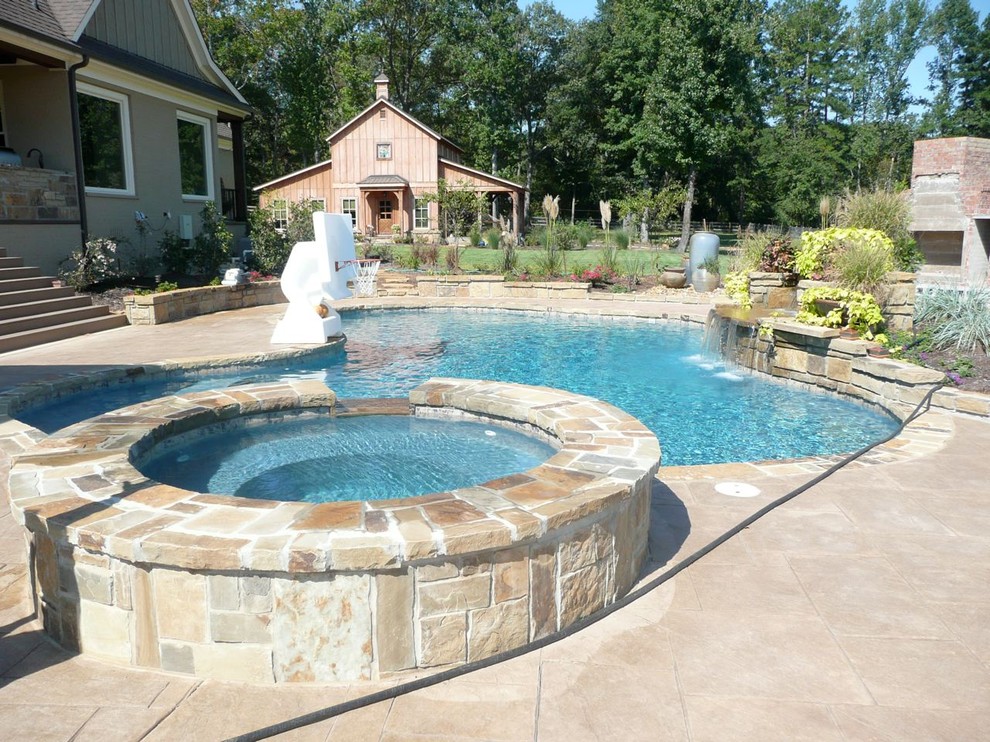 На фото: большой спортивный бассейн произвольной формы на заднем дворе в классическом стиле с джакузи и покрытием из плитки