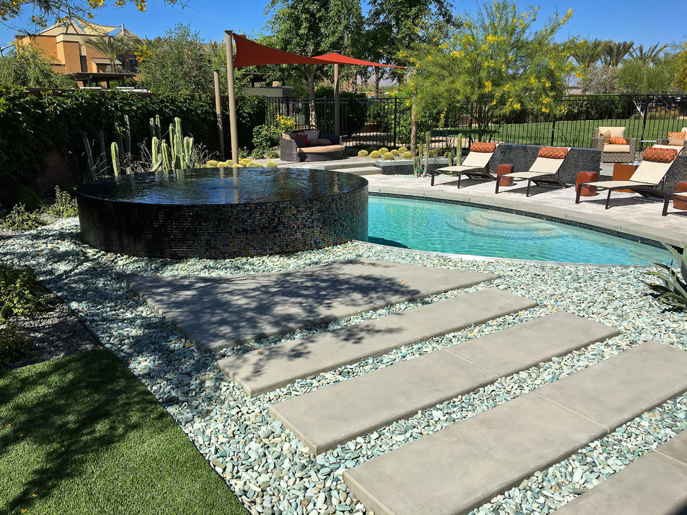 Diseño de piscinas y jacuzzis infinitos actuales de tamaño medio redondeados en patio trasero con suelo de baldosas
