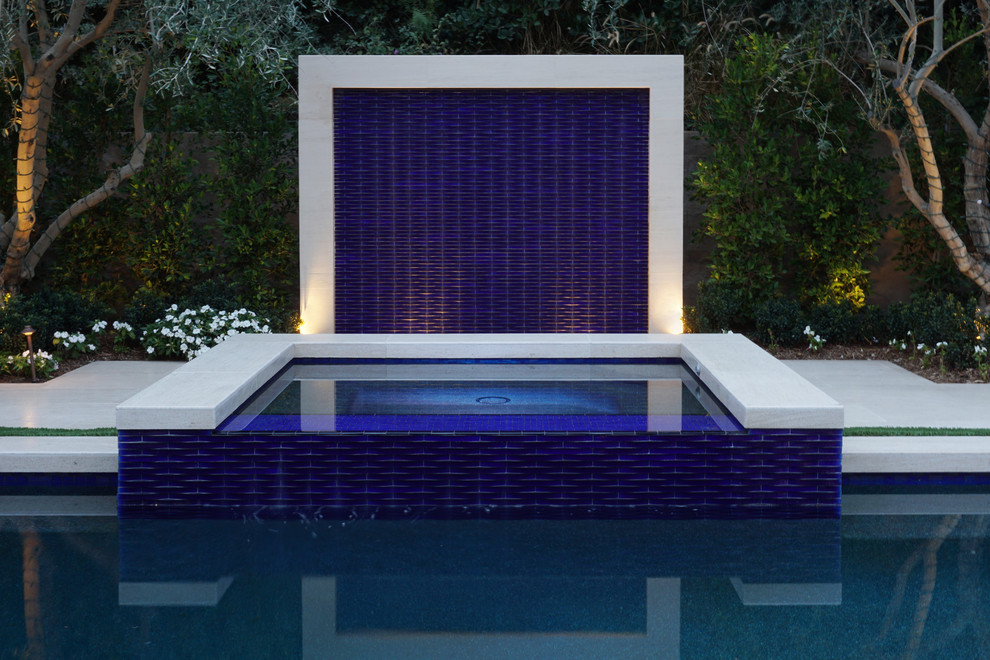 Ejemplo de piscina con fuente contemporánea grande rectangular en patio trasero con adoquines de piedra natural
